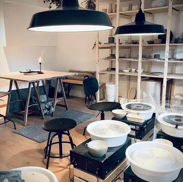 Töpferstudio mit Tischen und Regalen.