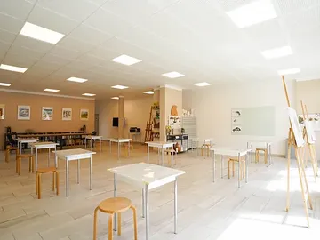 Empty classrooms with tables and chairs, brightly lit.