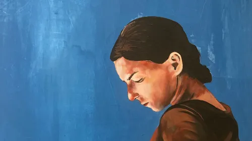 Woman looking down against a blue background.