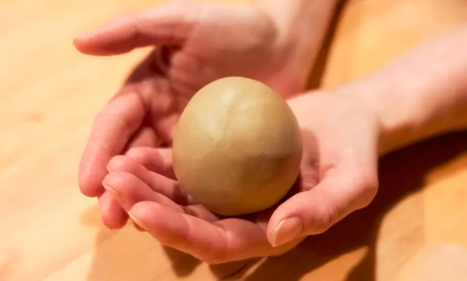 Hände halten einen Teigball.