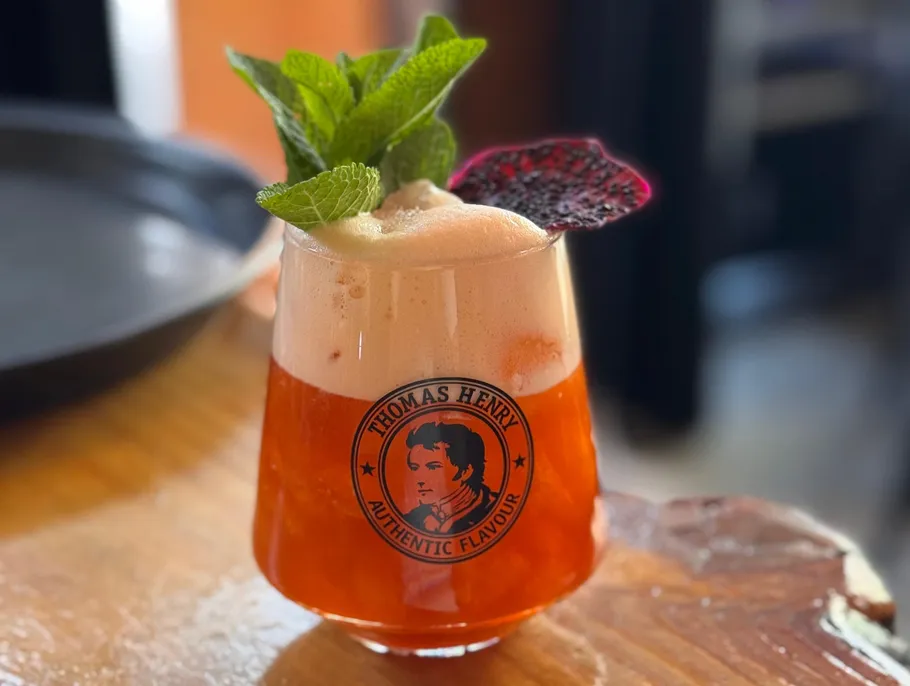 Cocktail mit Minzgarnitur auf Holztisch.