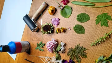 Flowers and leaves arranged on wooden table.