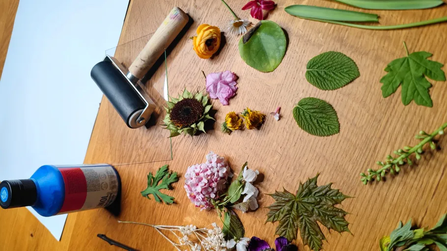 Blumen und Blätter auf Holztisch angeordnet.