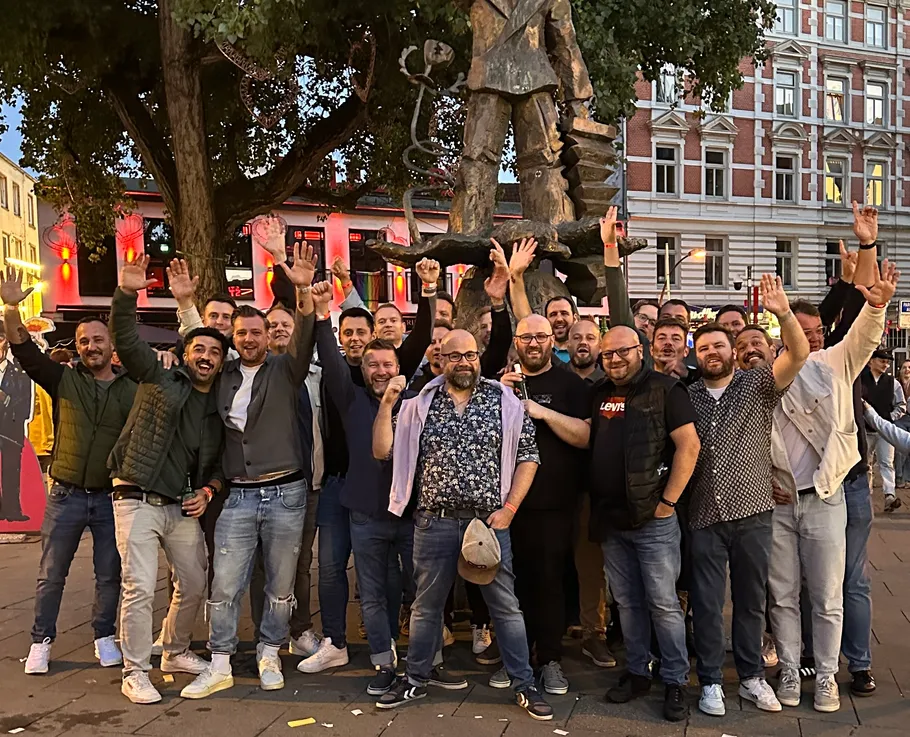 Group of men posing with hands raised outdoors.