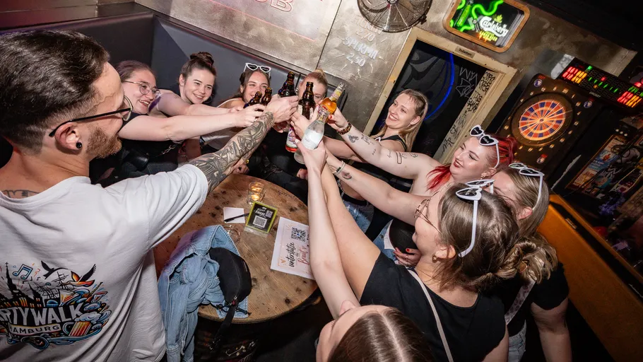 Group toasting with bottles in a bar.