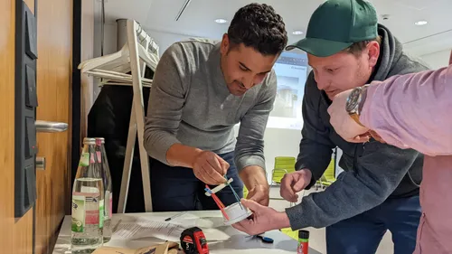 Two men assembling a small model indoors.
