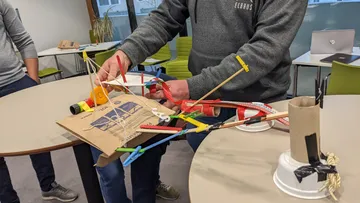 Personen bauen eine Struktur mit verschiedenen Materialien drinnen.
