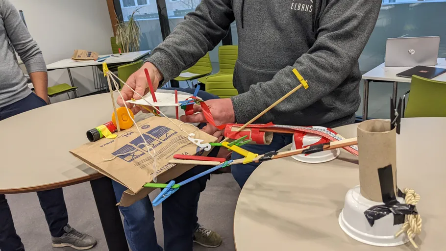 People building a structure with various materials indoors.
