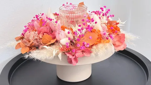 Glasvase mit Trockenblumen auf Tisch.
