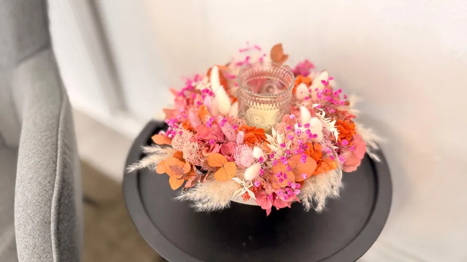 Colorful floral wreath with candle on table.