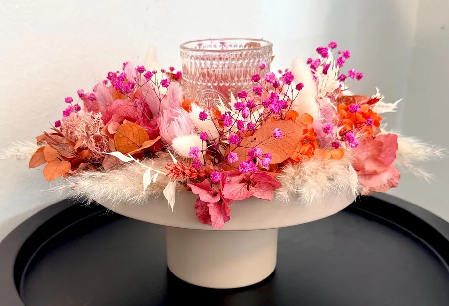Bunte Blumenarrangement mit Glashalter auf Podest.