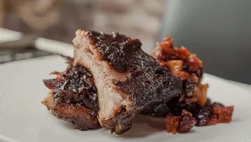 Barbecue-Rippen mit Soße auf weißem Teller.