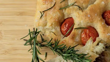 Focaccia mit Tomaten und Rosmarin auf Holz.