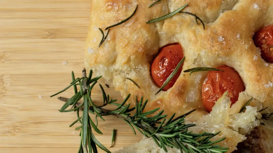 Focaccia with tomatoes and rosemary on wood.