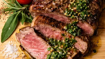 Grilled steak with herb sauce on board.