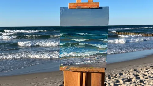 Painting of sea on beach easel.