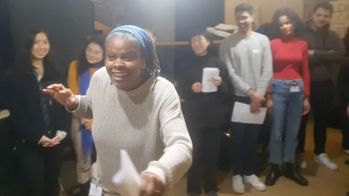 Woman speaking energetically to a smiling group.