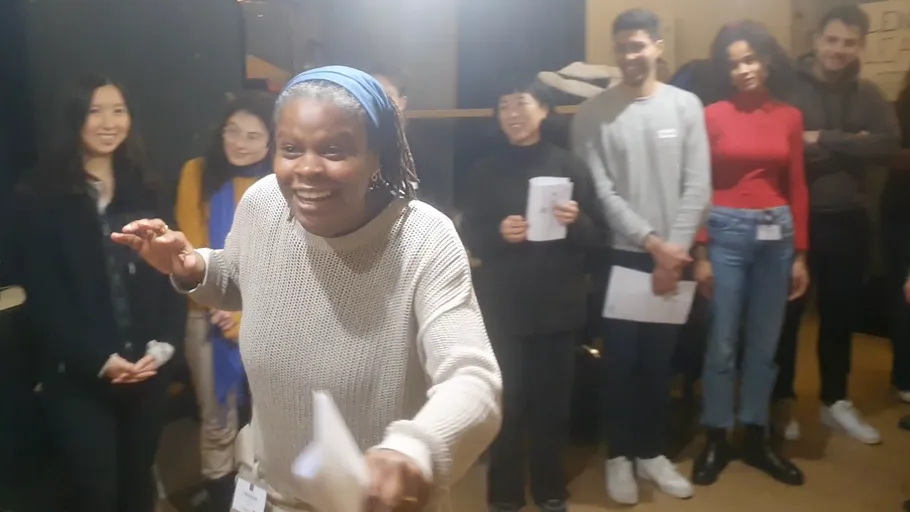 Woman speaking energetically to a smiling group.