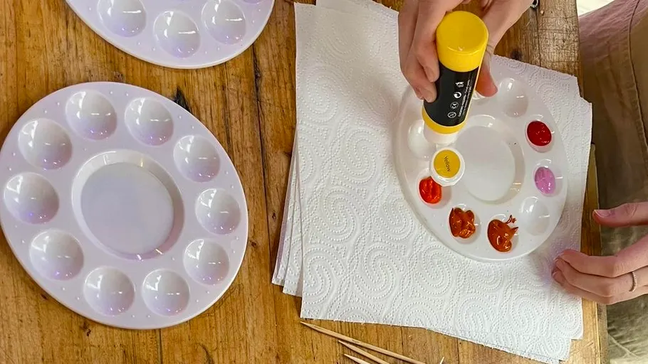 Person squeezing paint onto palette on table.