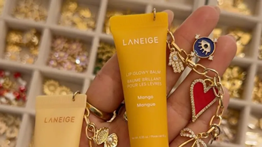 Hand hält Lippenbalsam vor Schmucktablett.