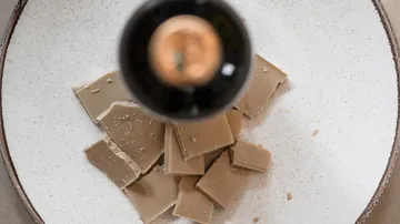 Chocolate pieces on a plate with overhead bottle.