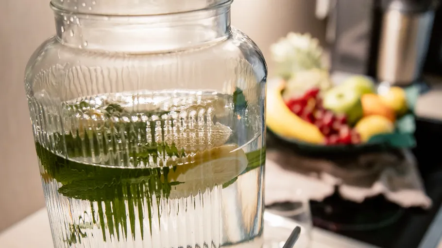 Glass jar with lemon water in kitchen.