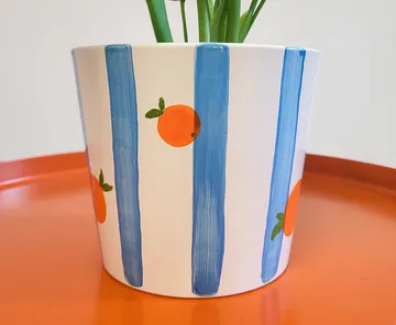 Painted flower pot with blue stripes, oranges.