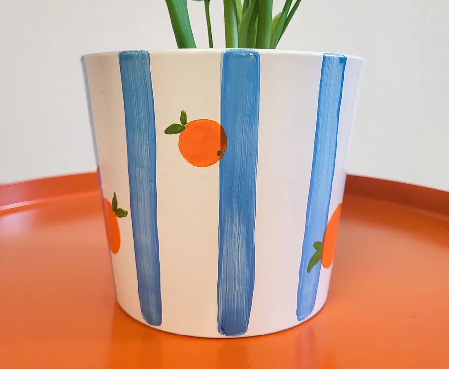 Painted flower pot with blue stripes, oranges.