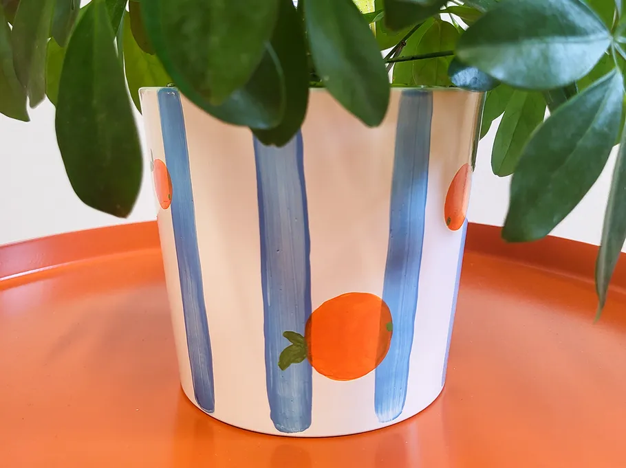 Bemalter Blumentopf mit blauen Streifen und Orangen.