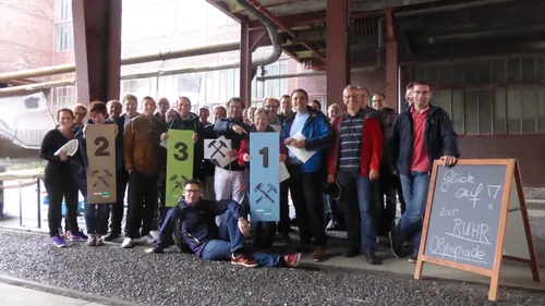 Group holding numbered signs in industrial setting.