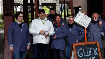 Group posing in striped shirts with a sign.