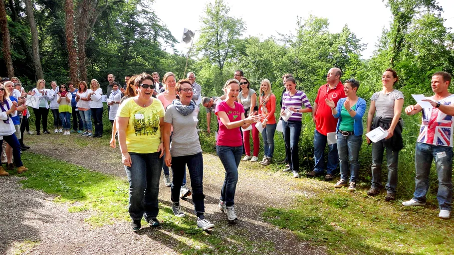 Menschen laufen im Freien, andere klatschen.