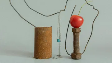 Rusty metal objects with cherry and necklace.