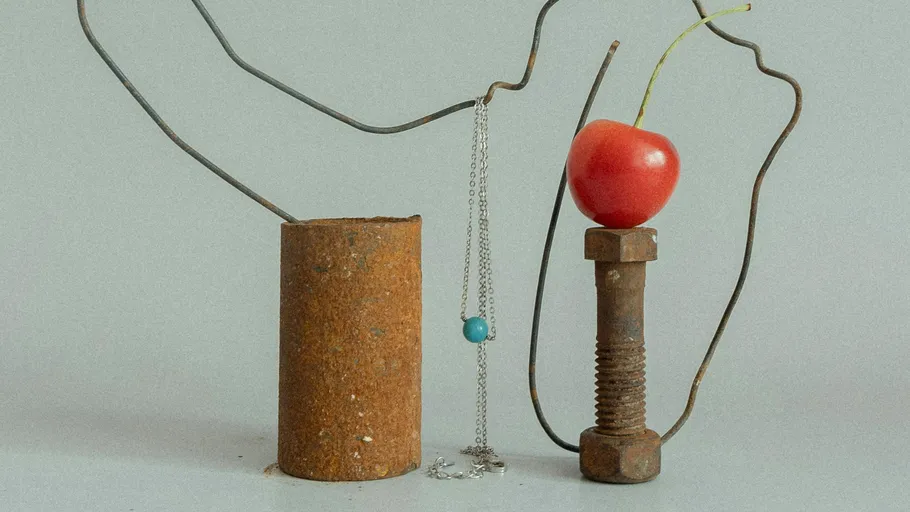 Rostige Metallgegenstände mit Kirsche und Halskette.