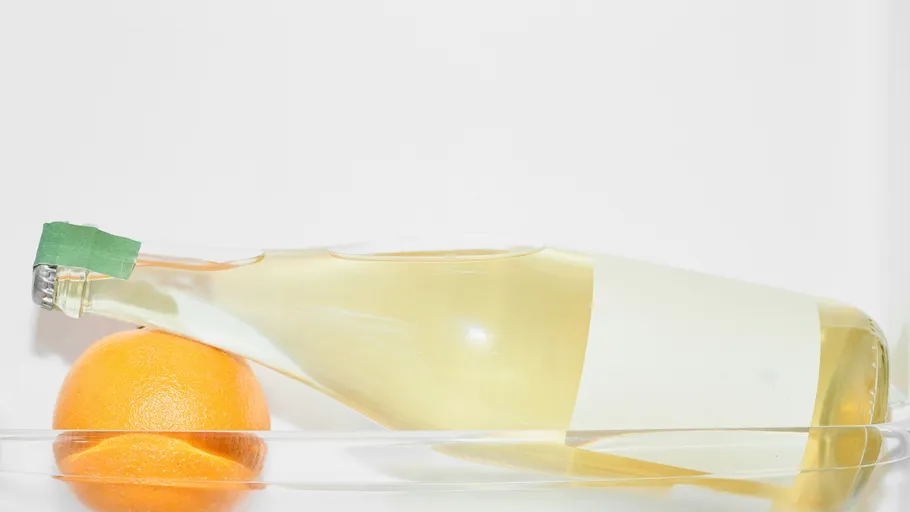 Flasche und Orange auf Glasoberfläche.