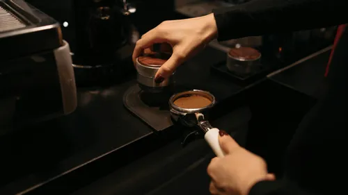 Barista drückt Kaffeepulver im Siebträger an.