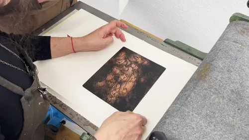 Person untersucht Kunstwerk auf Druckerpresse.