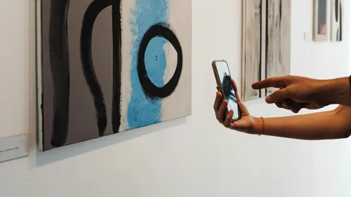 Person fotografiert abstraktes Gemälde in Kunstgalerie.