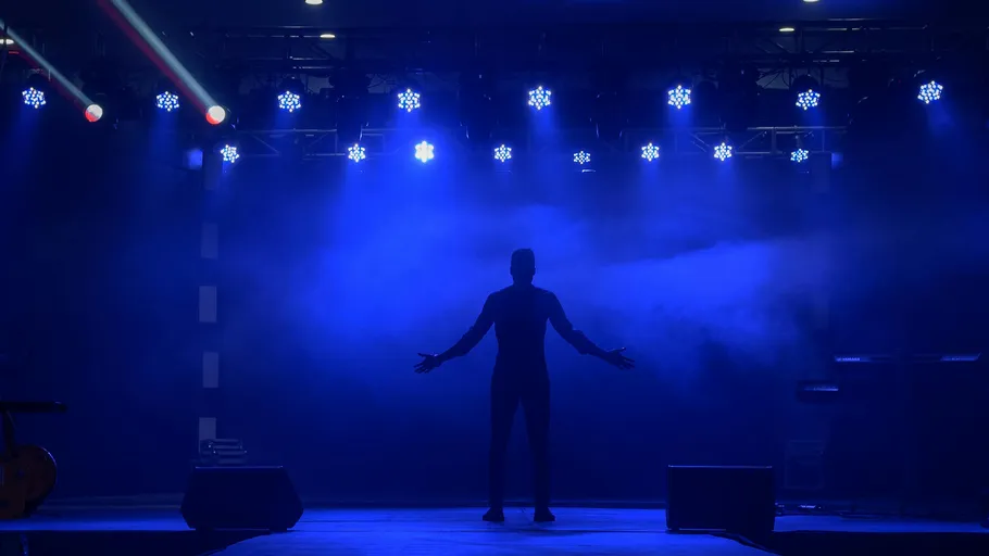 Silhouette eines Künstlers auf einer Bühne mit blauem Licht.
