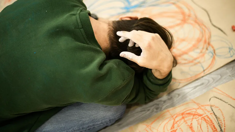 Person in green shirt crouching on colorful floor.