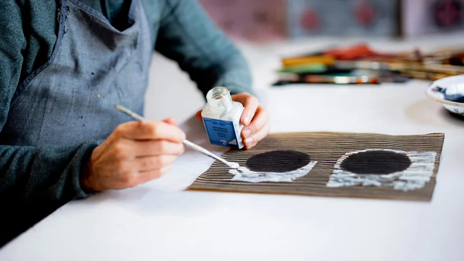 Person painting on striped paper with brush.