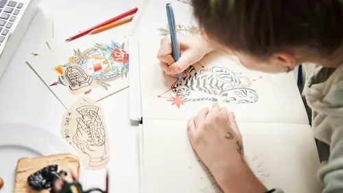 Person drawing in sketchbook with colorful designs.
