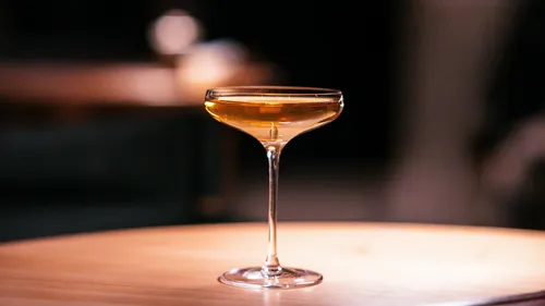 Cocktailglas mit Getränk auf Holztisch.