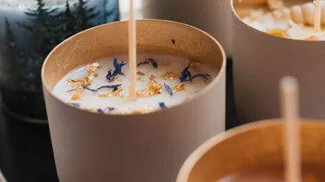 Decorative candles with dried herbs and gold flecks.