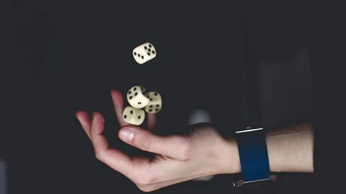 Hand wirft vier Würfel in die Luft.