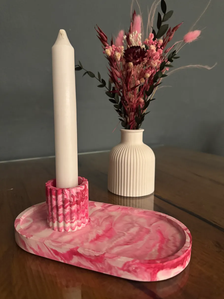 Weiße Kerze auf pinkem Halter, Vase mit Blumen.
