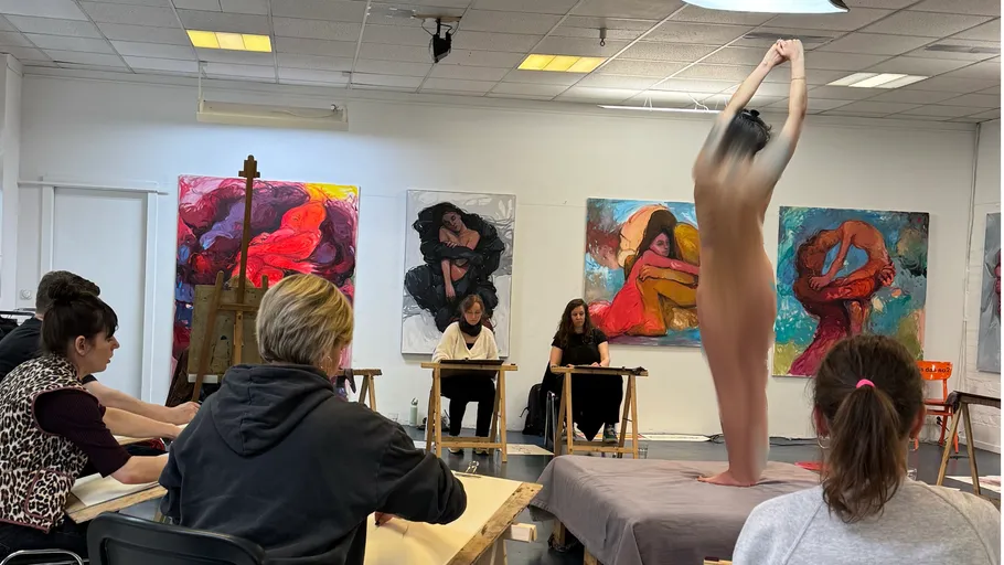 Art class with model posing, participants drawing.