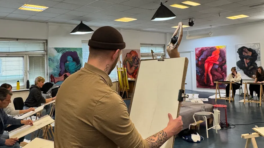 Personen skizzieren ein Modell in einem Kunstkurs.