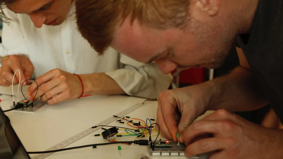 Zwei Personen bauen Elektronik auf einem Tisch zusammen.
