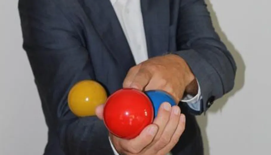 Mann jongliert bunte Bälle drinnen.